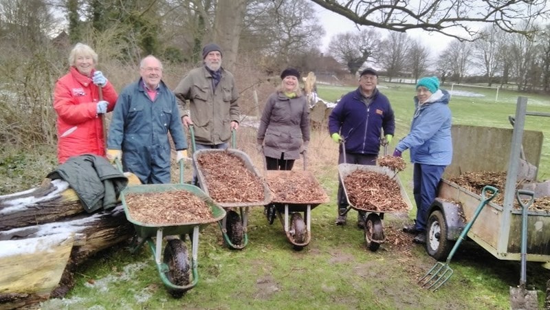 5 people with wheelbarrows full of woodchip to renew the woodland path