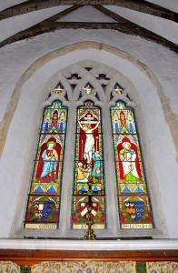 A picture of the main stained glass window at St Peter's Carlton, sunlit from behind